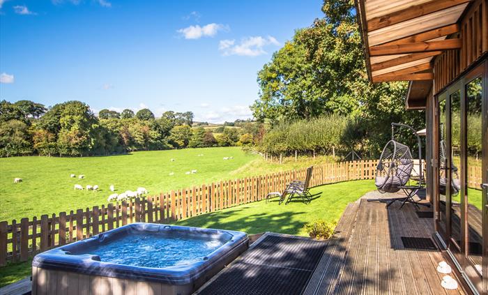 Sycamore Lodge veranda with views across fields and sheep grazing.